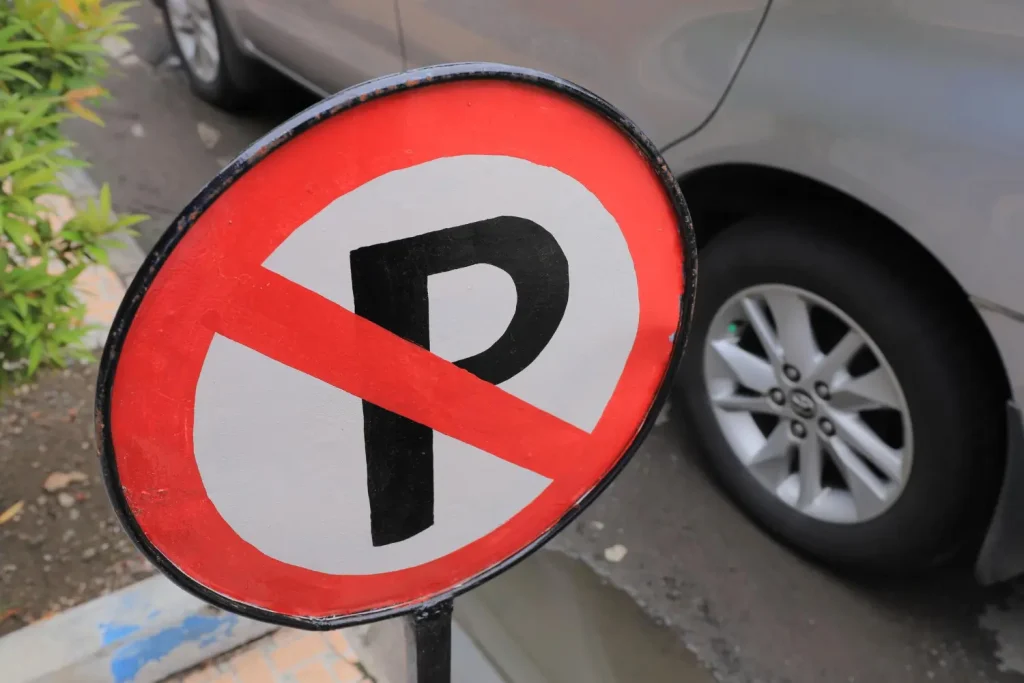 Illegal parking sign with car parked beside it