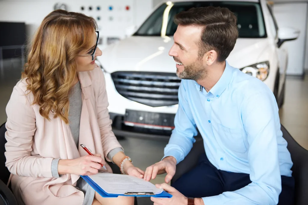 lady signing car finance papers with a sales assistant
