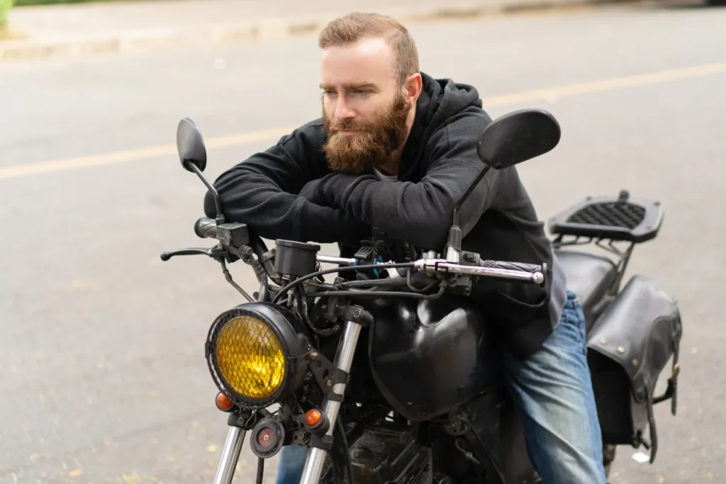 man on stationary motorbike with his arms on handlebars looking straight ahead